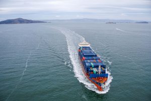 A large container ship navigating in open water, representing industries benefiting from vibration monitoring for machinery health.